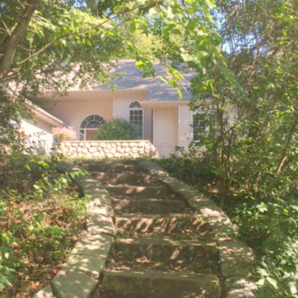 European country cottage exterior with stone steps leading to courtyard entrance with stone wall - Hello Lovely Studio.