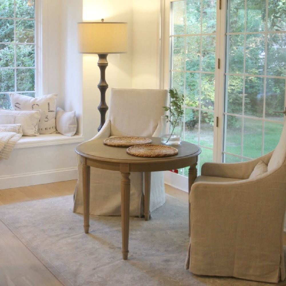 Benjamin Moore White OC-151 in kitchen. Belgian linen slope arm dining chairs in our breakfast nook with window seat - Hello Lovely.