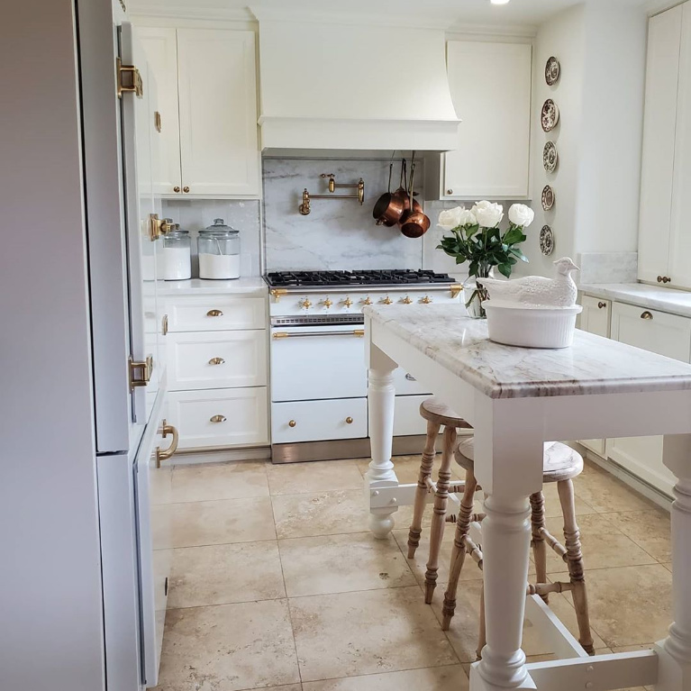 White French kitchen with Lacanche range, island and rustic wood farmhouse stools - The French Nest Co Interior Design. #whitekitchen #kitchendesign #frenchkitchens #lacanche #frenchcountry #interiordesign #modernfrench