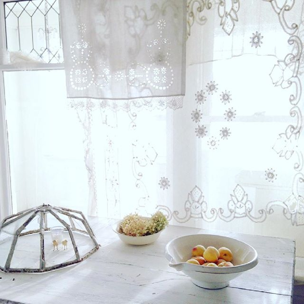 French antiques and vintage kitchenwares in an all white country kitchen with sheer lace curtains - My Petite Maison.