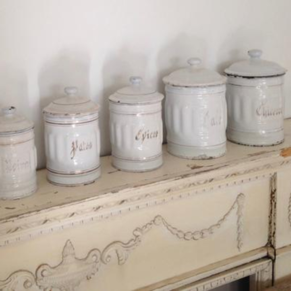 Vintage French white canisters on a fireplace mantel styled by @mypetitemaison. #frenchvintage #frenchkitchendecor