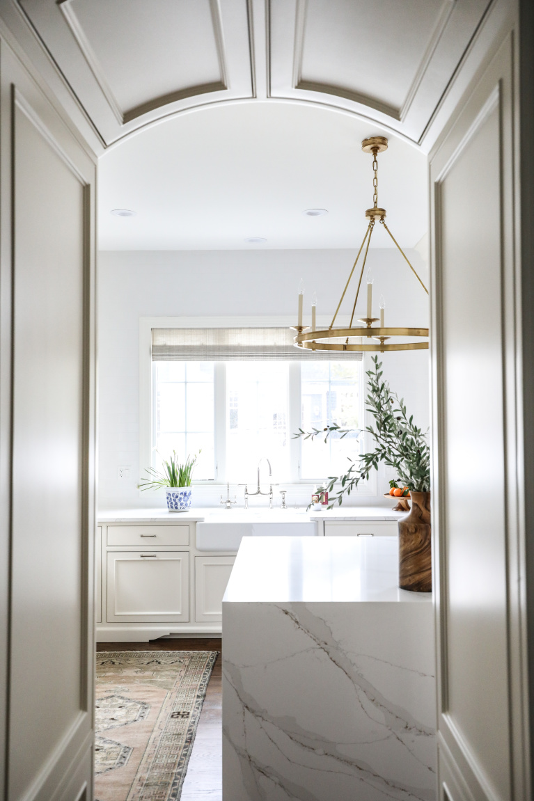 Simple yet sophisticated white elegant kitchen with brass hardware, waterfall island, and farm sink - Park and Oak. #kitchendesign #classickitchen #whitekitchen #waterfallisland ##farmsink #elegantkitchen