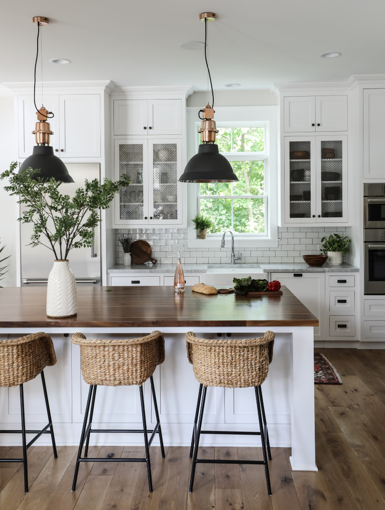 Simple yet sophisticated white modern farmhouse kitchen with wood topped island and rattan stools - Park and Oak. #kitchendesign #classickitchen #whitekitchen #coastalkitchen #whiteoak #modernfarmhouse