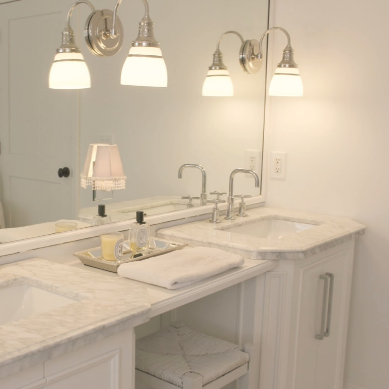Traditional freestanding white single vanity with makeup counter in our French country bathroom with calacatta like porcelain tile. #hellolovelystudio #bathroomdesign #whitevanities #carraramarble #makeupcounter #hisandhervanities