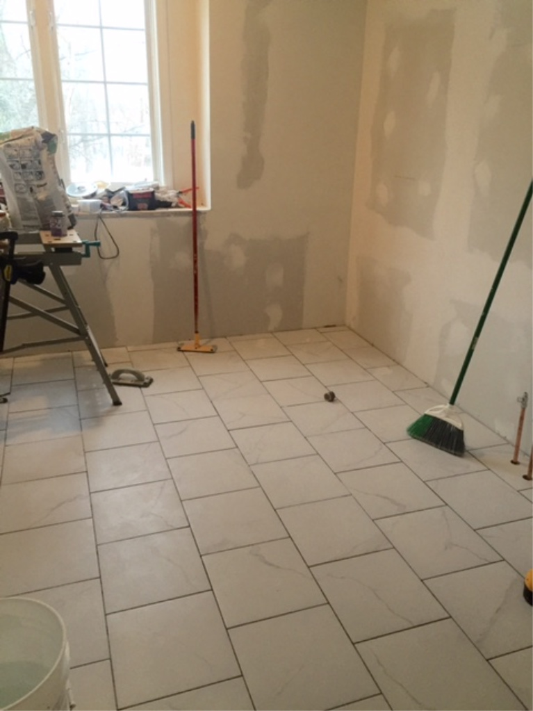 before pic during Hello Lovely's master bathroom renovation when calacatta-look porcelain floor tile installed.