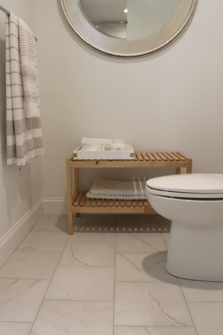 Calacatta-look porcelain floor tiles, Ikea Molger wood bench for towels, and Kohler toilet in our master bath. #hellolovelystudio #bathroomdesign #ikea #molger #bench