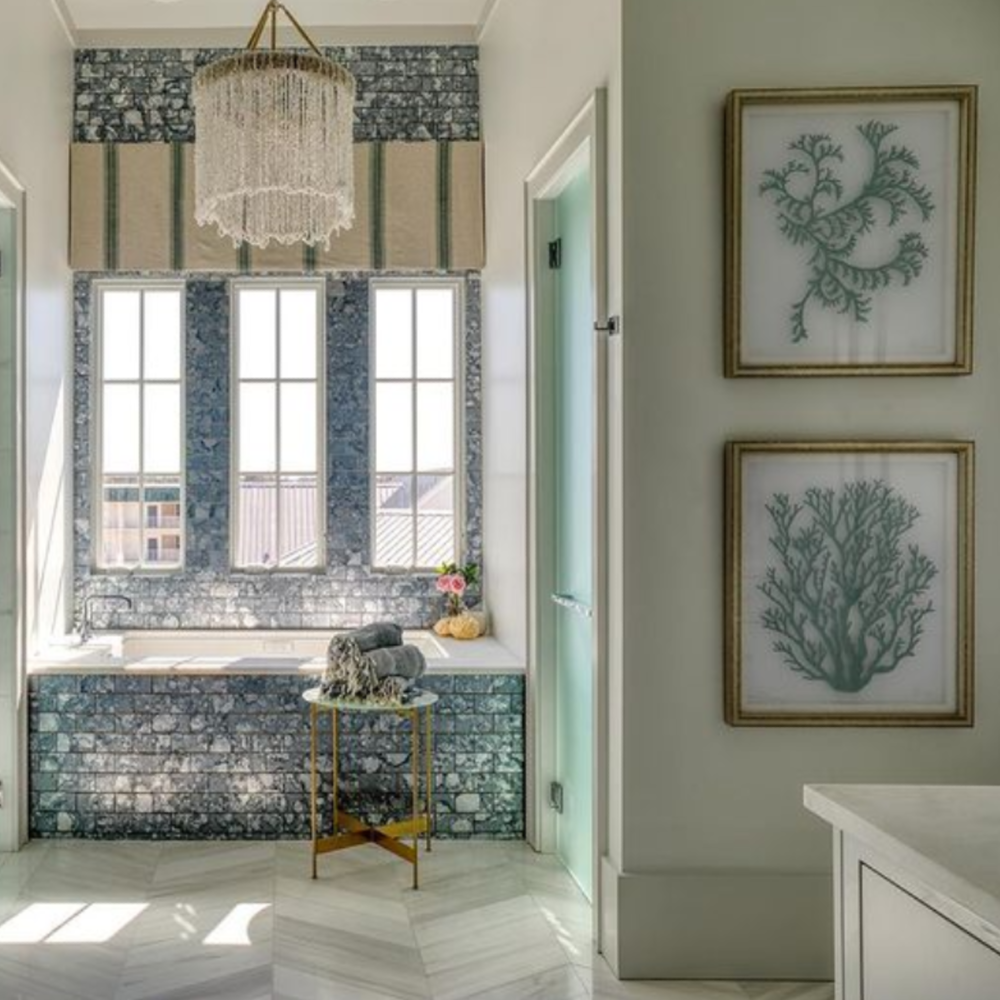 Stone tile floor to ceiling in a luxurious blue and white coastal bath with architecture by Geoff Chick.