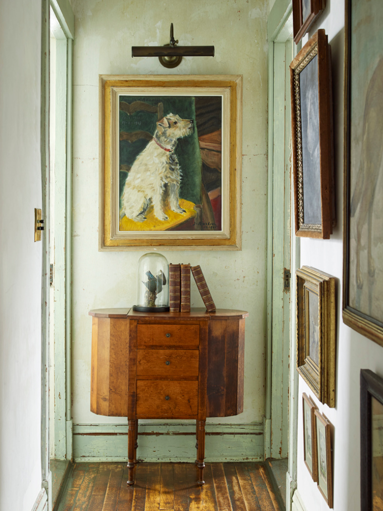 Collection of dog portraits in the hallway of a Provincetown seaside summer home with interiors by Ken Fulk. Photo by Tria Giovan for Jennifer Ash Rudick's Summer to Summer. #dogpaintings #interiordesign #dogportrait #kenfulk #vintagestyle #traditionaldecor