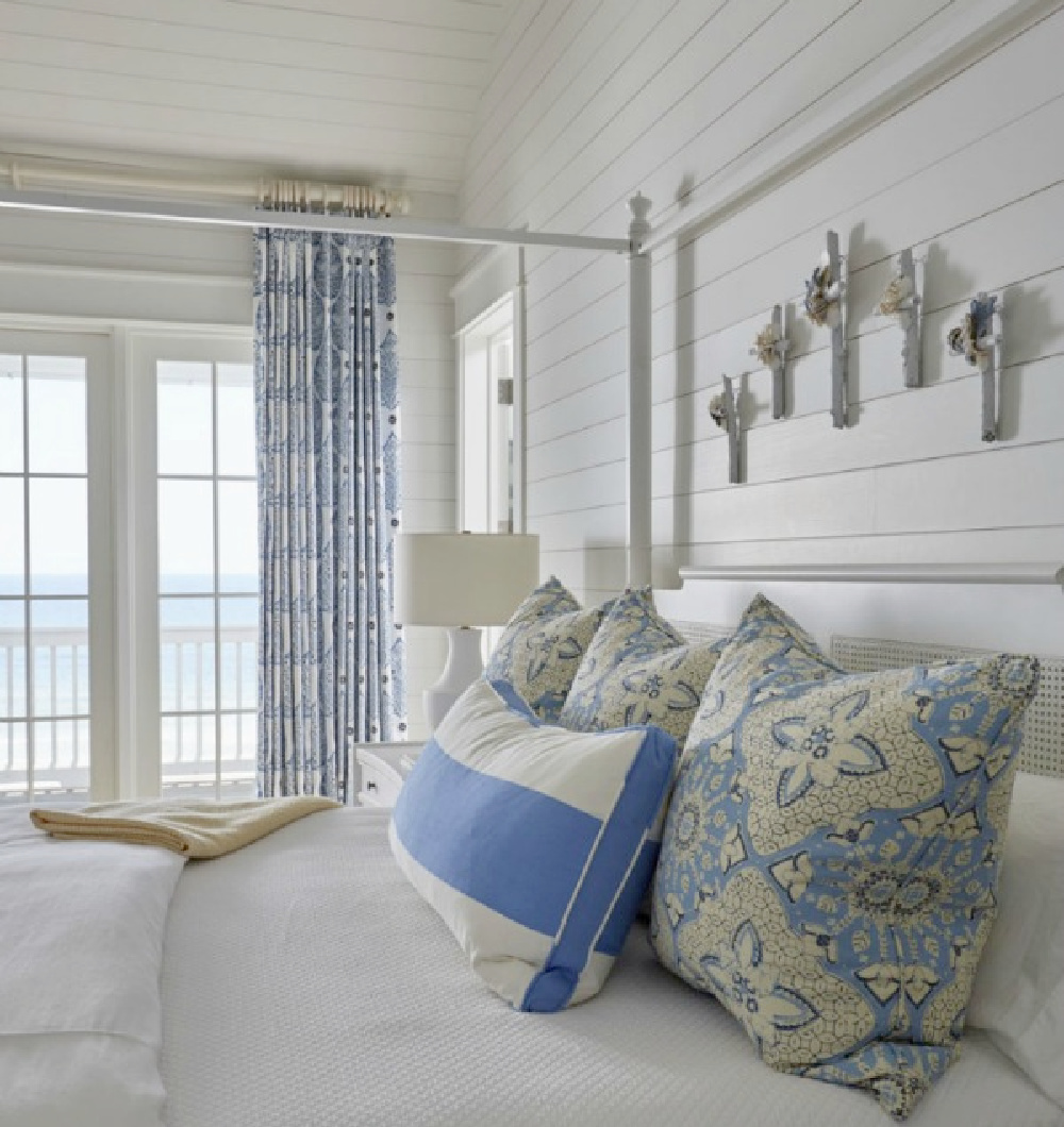 Luxurious and lovely coastal bedroom with blue tripe pillow, shiplap walls, and architecture by Geoff Chick.