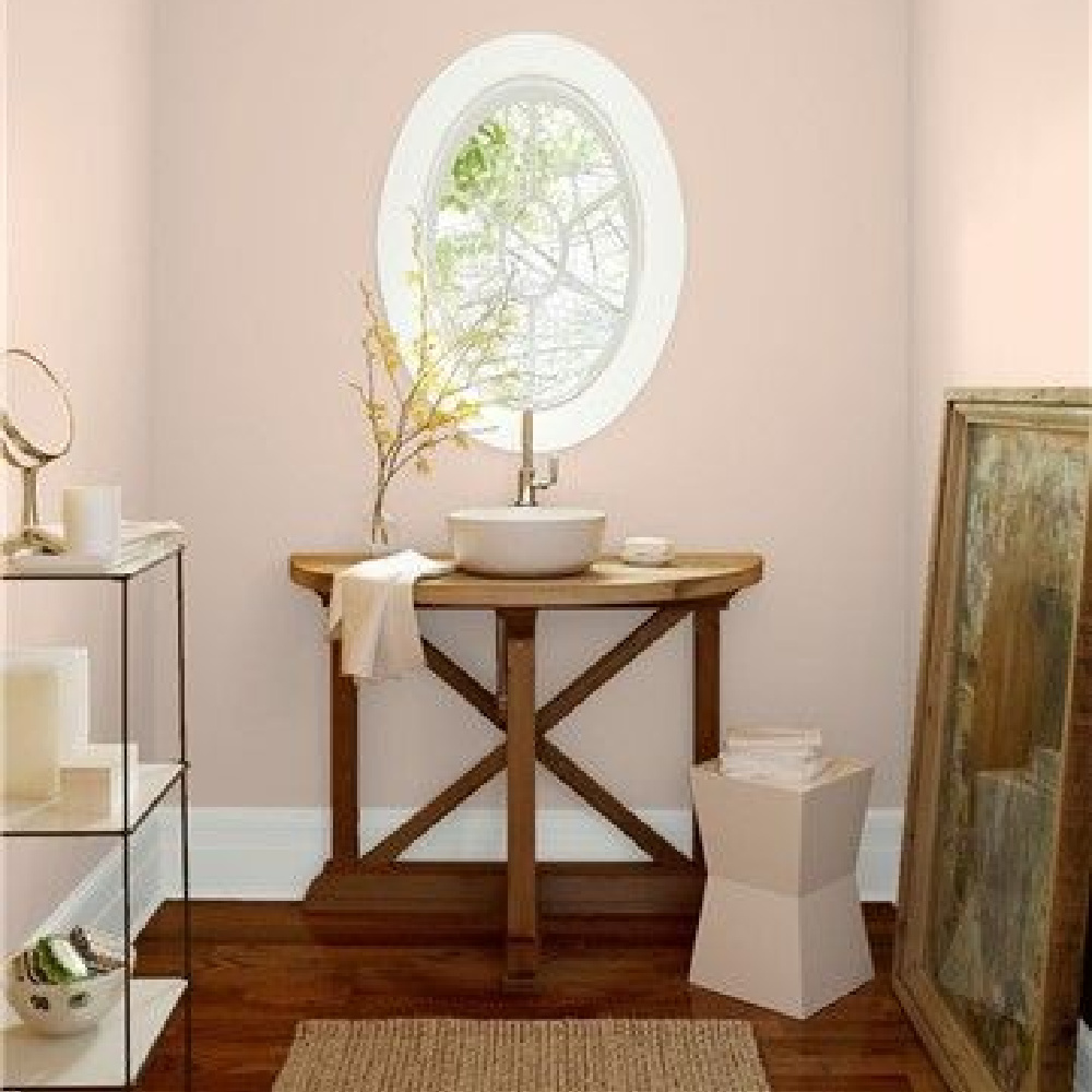 Coastal Cottage (Benjamin Moore) pink paint color on walls of a bathroom with oval window. #coastalcottage #pinkpaint