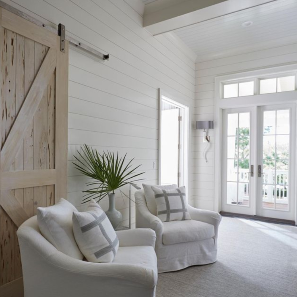 Classic coastal interior with white shiplap, rustic barn door and French doors - architecture by Geoff Chick.