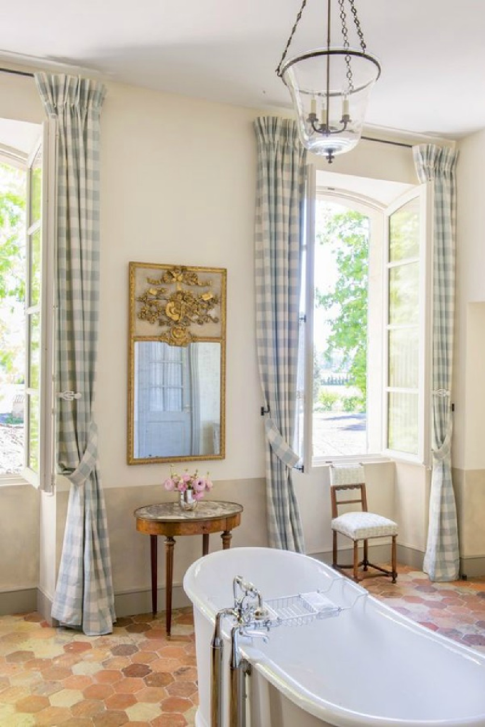 Blue check curtains, terracotta hex tiles, and clawfoot tub in a Provence farmhouse (Le Mas des Poiriers).