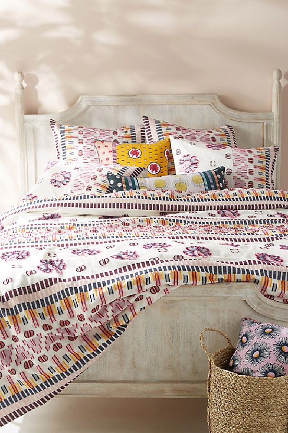 Pink Ground No.202 - Farrow & Ball paint in a bedroom with colorful print bedspread and distressed panel bed.