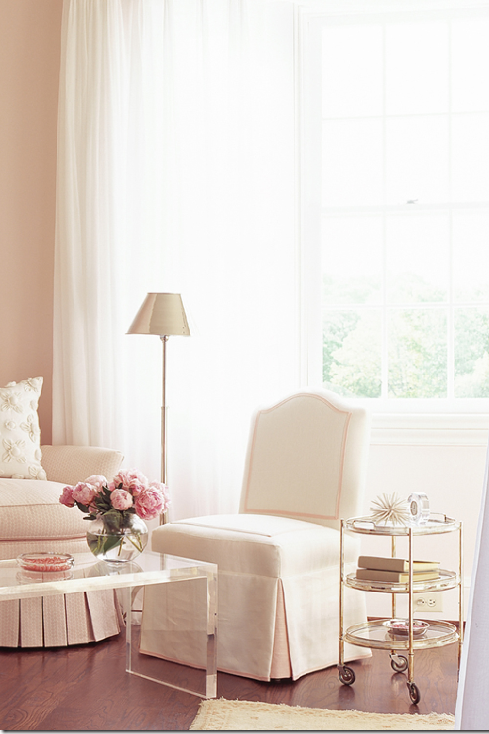 Gorgeous classic room design with blush pink walls, slipper chair, and acrylic coffee table. Design by Phoebe Howard. Come see the Best Sophisticated, Chic and Subtle Pink Paint Colors on Hello Lovely Studio!