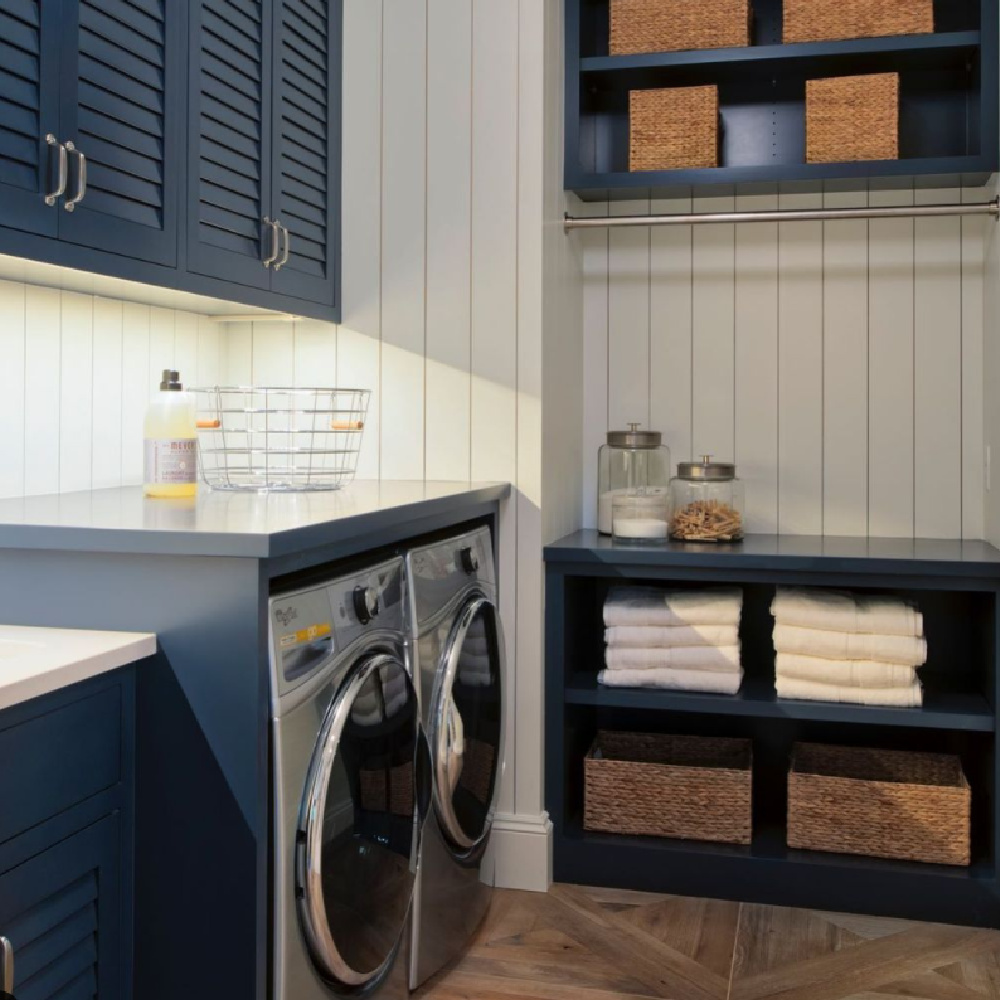 Coastal laundry room with navy blue plantation style cabinets, shiplap, and smart storage - StudioMInteriors. #dreamlaundryroom #navyblue