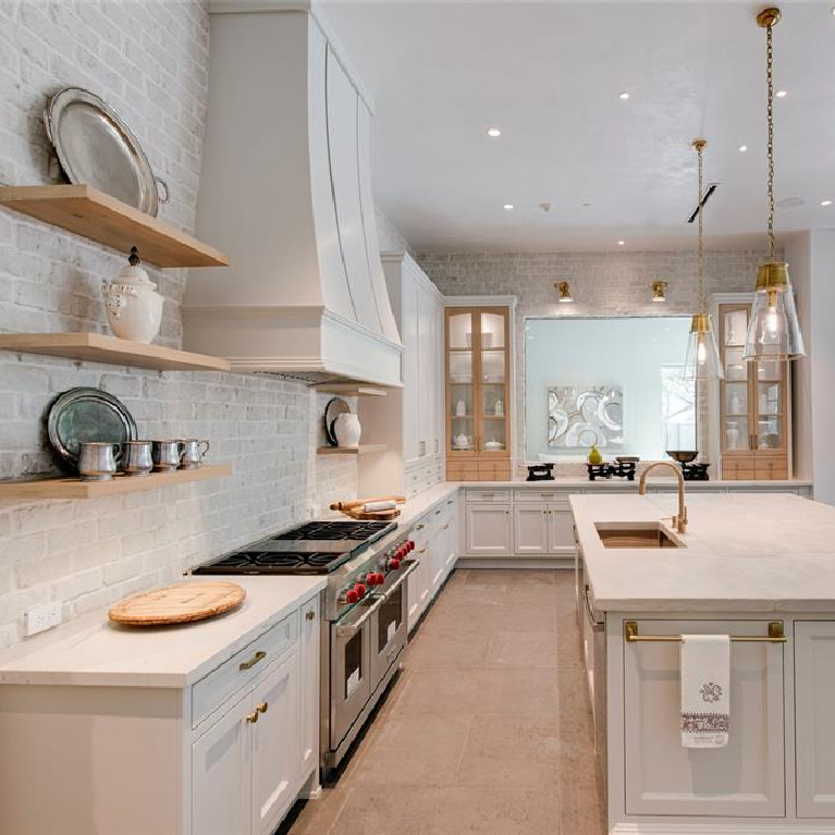 Brick tiled wall in serene timeless kitchen design in stunning French inspired luxury home in Houston. 