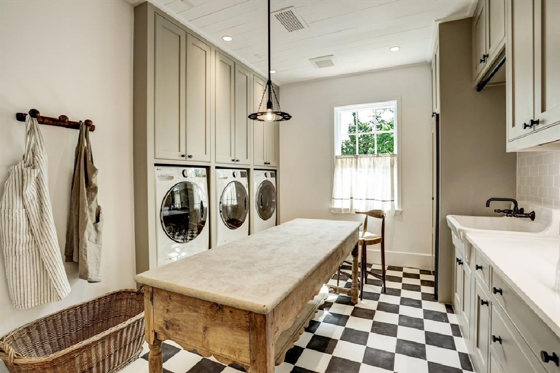 Laundry room with antique table and checker flooring in MILIEU Showhouse 2020 - featuring exceptional designers including Darryl Carter, Kathryn Ireland, Pamela Pierce, Shannon Bowers, and more. #milieushowhouse #interiordesign #designershowhouse #luxuryhome #edwinlutyens #houstonhome #laundryrooms