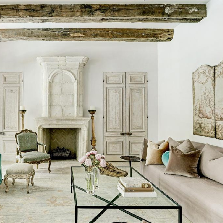 Stunning and sophisticated family room in a French inspired home with 18th century limestone fireplace and rustic ceiling beams. #frenchcountry #interiordesign #luxuryhome #antiques #europeancountry