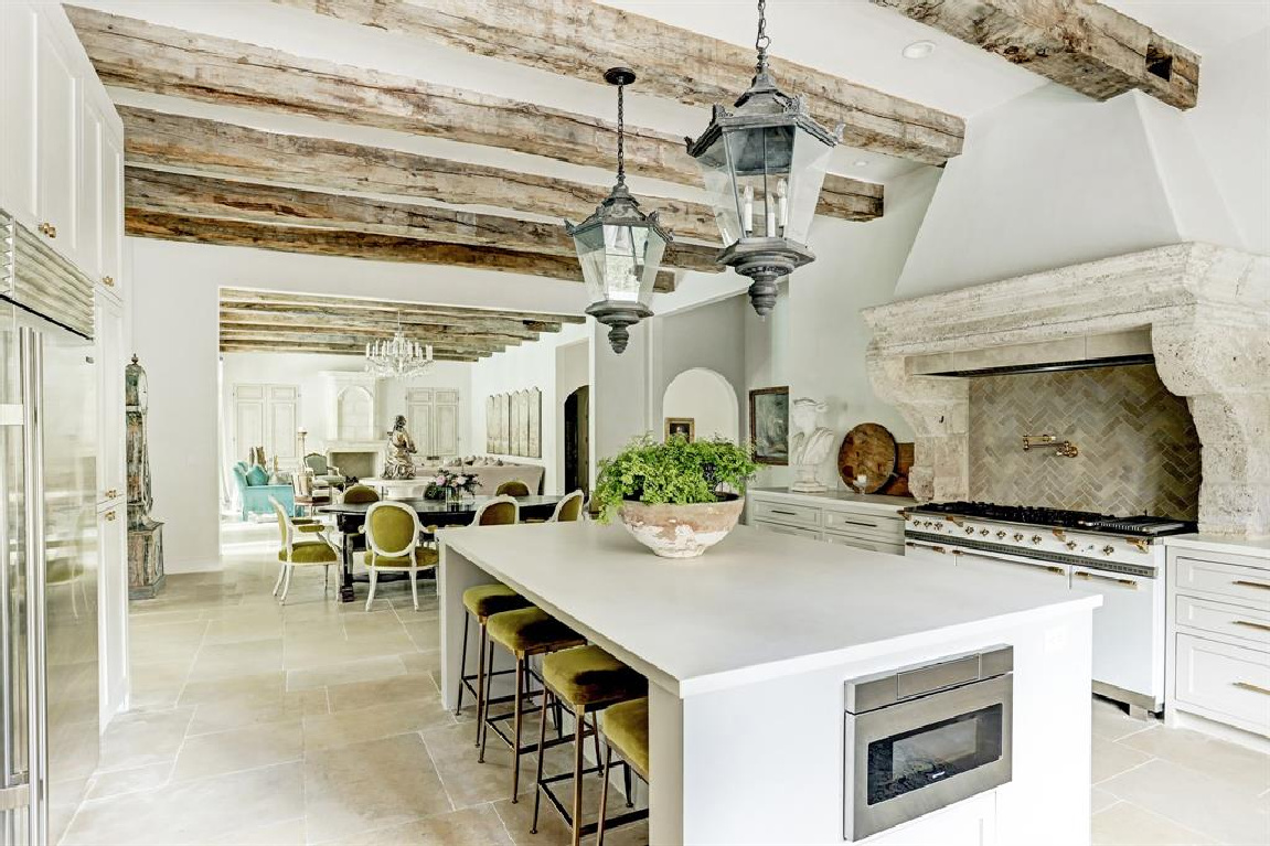 Rustic wood beams and antique street lights from Barcelona in Pale and serene French interiors in a luxurious Houston home built with authentic European materials and bespoke finishes. #timelessdesign #interiordesign #frenchcountry #europeancountry #antiques #oldworldstyle #modernfrench #frenchkitchen