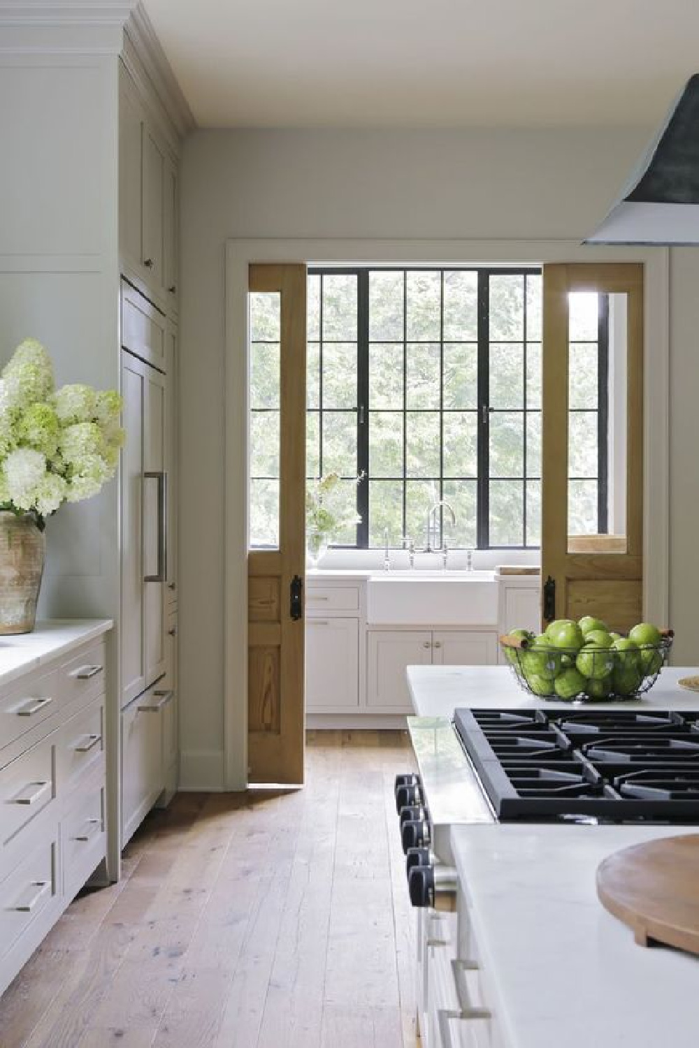 Breathtaking classic country kitchen with farm sink, wood tone pocket doors, steel windows, and putty cabinets - Rachel Halvorson. #countrykitchens #pocketdoors #kitchenarchitecture