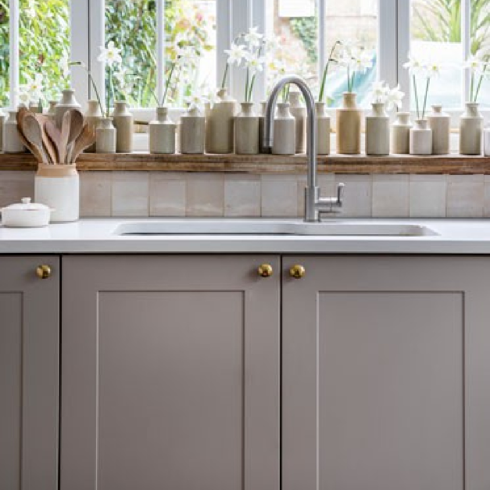 Zellige tile backsplash in a gray English country kitchen with a collection of stoneware bottles - ImperfectInteriors. #zellige #englishcountry #kitchendecor