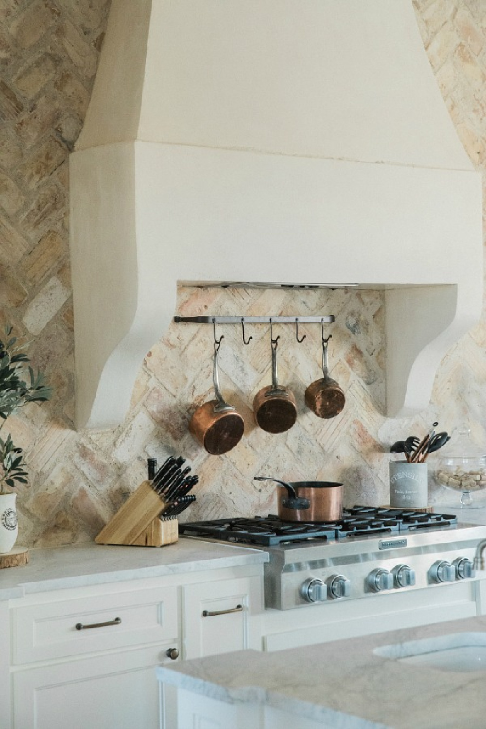 Rustic elegant French country farmhouse kitchen with beautiful stucco range hood, copper pots, reclaimed Chicago brick backsplash, arabescato marble counters, and lanterns over island. Brit Jones Design. See more Gorgeous European Country Interior Design Inspiration on Hello Lovely. #europeancountry #frenchfarmhouse #interiordesign
