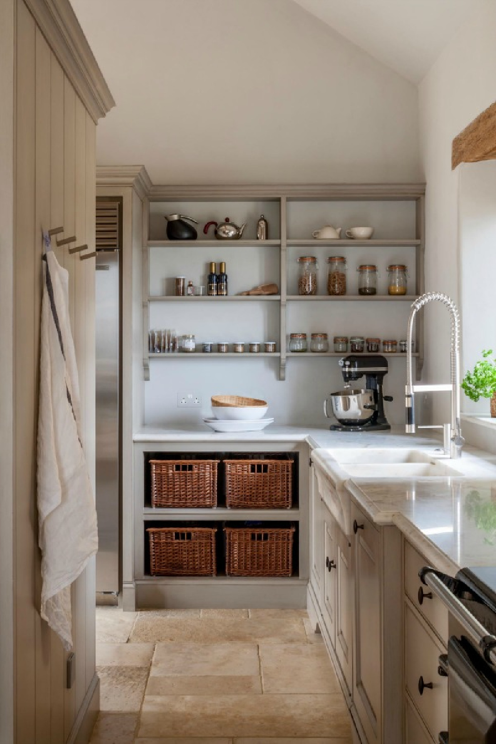 Bespoke kitchen with Flemish design influences and French farmhouse style. Design by Artichoke. Stone flooring, painted cabinets, open shelving, and rustic baskets. #frenchfarmhouse #kitchendesign