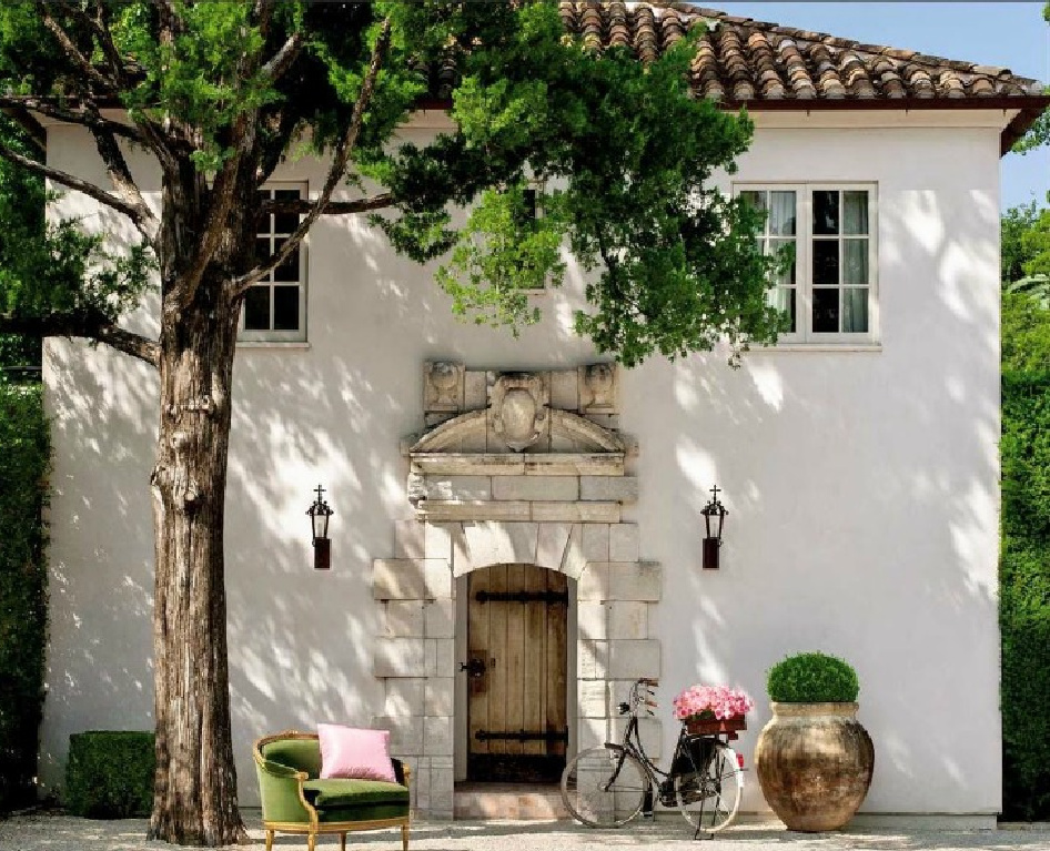 Charming white stucco French cottage with ancient stone clad entrance and lanterns. #reaganandre #frenchcottage #milieu #pamelapierce #houstonhome #chateaudomingue