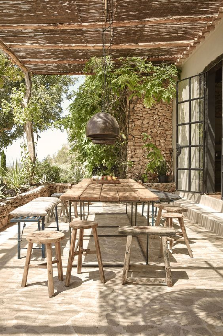 Rustic wood benches and stools at farm table on a Tuscan patio. #tuscanstyle #rustic #outdoordining #farmhouse #italianrustic