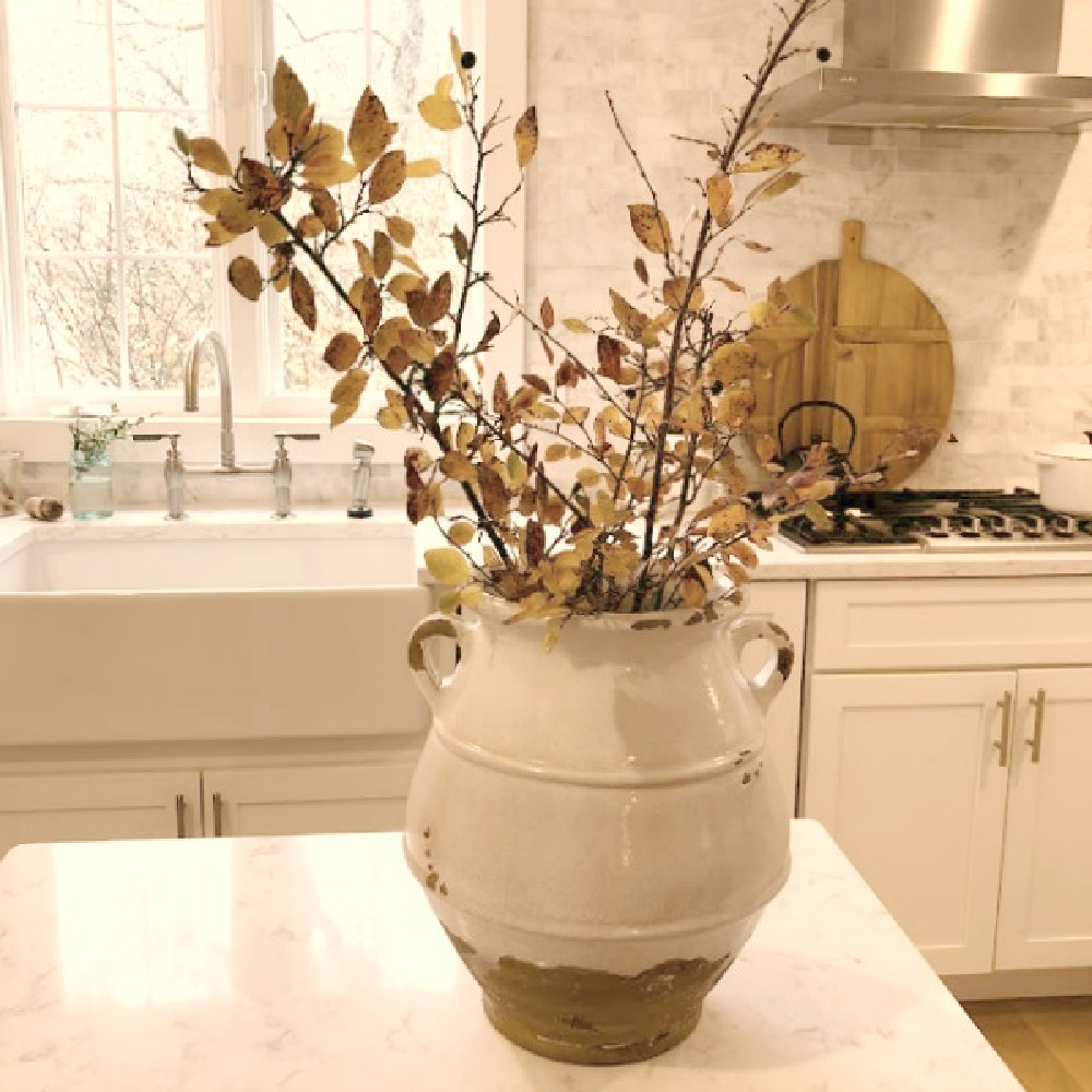 Terracotta urn with fall branches on the work table in my white European country modern French kitchen - Hello Lovely.