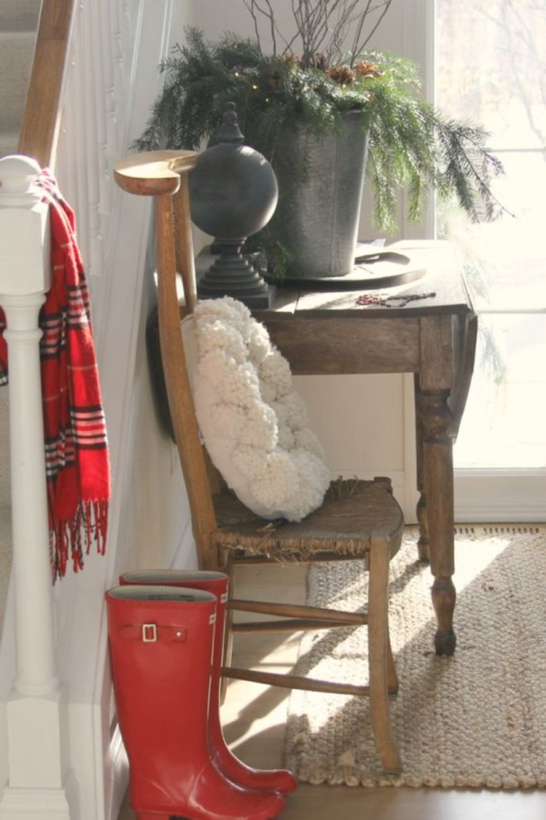 Christmas decor in Hello Lovely's entry is as simple as red boots, plaid scarf, and pom pom wreath. #hellolovelystudio #christmasdecor #holidaydecorating #simplechristmas #pompomwreath #redboots #holidayhomes and