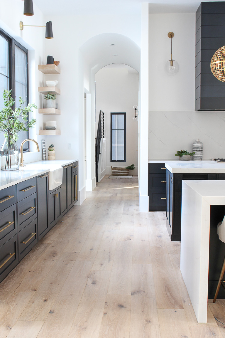 Bright white walls (Sherwin Williams Pure White) and black cabinets in a lovely kitchen by House of Silver Lining. #sherwinwilliamspurewhite #whitepaint #paintcolors #bestwhite