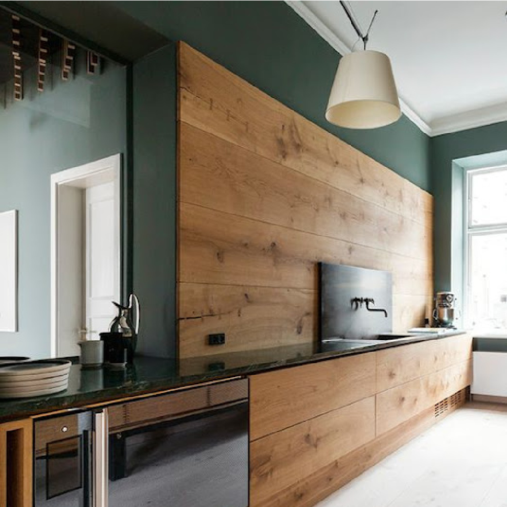 Deep and dark green walls in a rustic kitchen with wood backsplash by dinesen - Come explore Dark Green Paint, Autumnal Greens & Interior Design Inspiration!