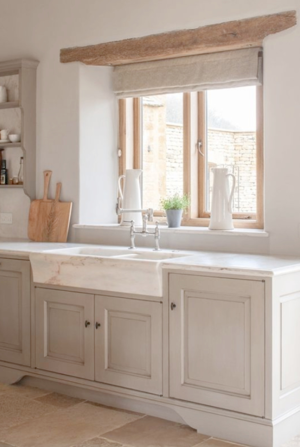 Bespoke kitchen design by Artichoke in this Old World space with Bentall marble sink, stone floor, and pale cupboards. #marblesink #bespokekitchen