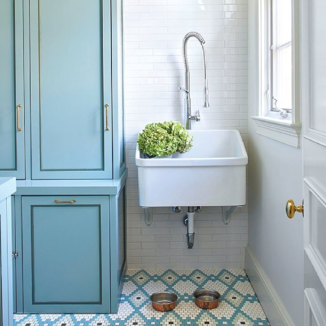 Laundry room with Swedish blue cabinets, whimsical patterned tile floor, and country sink with modern faucet - Birmingham Home & Garden. #laundryrooms #mudrooms #interiordesign