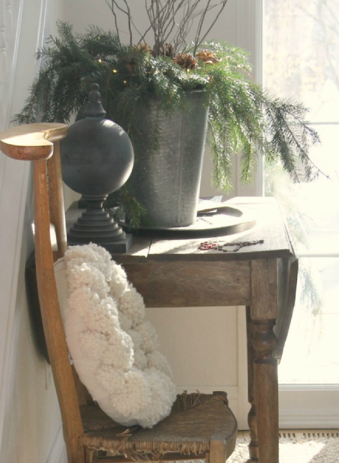 Hello Lovely's holiday decor with pom pom wreath on French prayer chair with vintage table in entry. #holidaydecor #pompomwerath