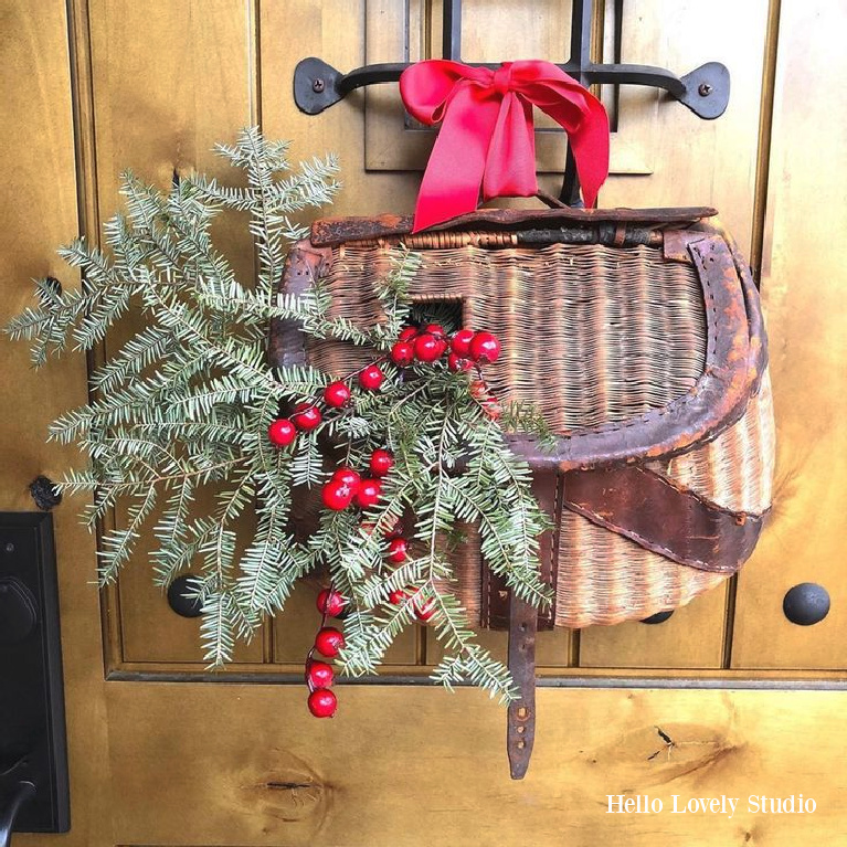 My alder front door with speakeasy with Christmas greenery and berries in vintage woven fishing basket - Hello Lovely Studio. #frontdoor #christmasdecor #holidaywreath #doordecor