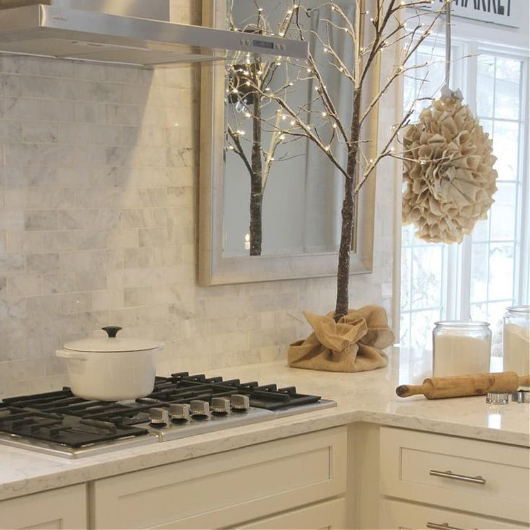 Scandinavian Christmas white kitchen with vintage book page wreath and winter tree on counter - Hello Lovely Studio. #holidaydecor #christmaskitchen #scandinavianchristmas