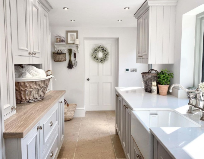 Serene laundry room with light grey cabinetry, farm sink, and galley style - Katy Harwood. #laundryrooms #farmhouselaundryroom