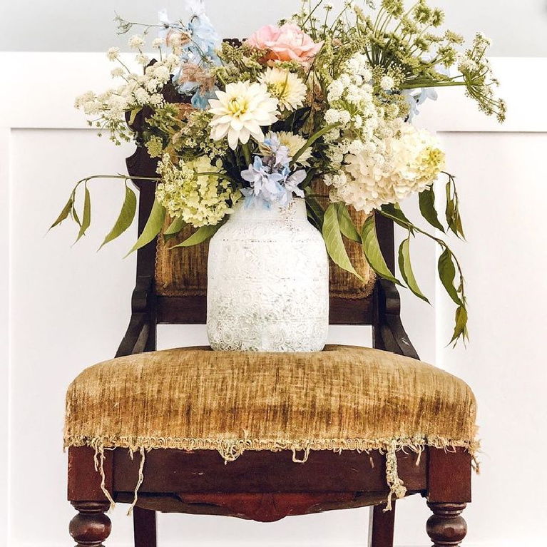 Romantic French farmhouse blooms in rustic vase upon vintage tattered velvet chair - Le Cultivateur.