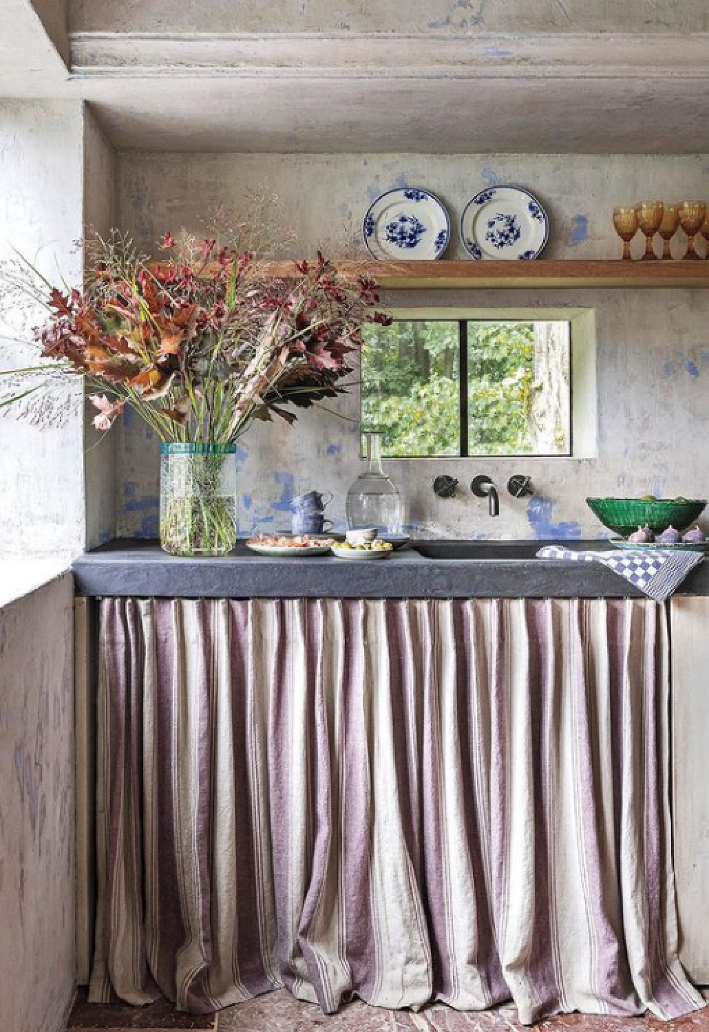 Rustic luxe Belgian style decor with skirted sink, stone, and shelf in a pool house in Belgium - design by Greet Lefevre; photo by Claude Smekens - in Milieu Summer 2021. #belgianstyle #skirtedsink #interiordesign