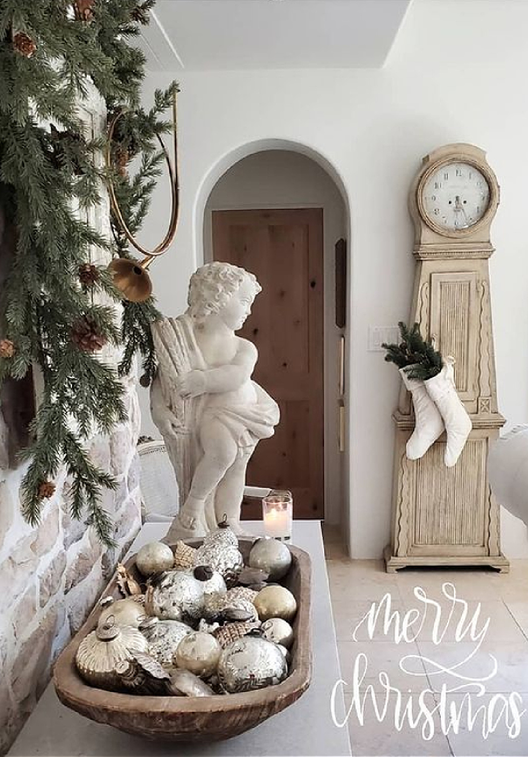 Breathtaking French country Christmas decor with white stockings hung from Swedish clock, cherub, wreath, and dough bowl with silver balls - The French Nest Co Interior Design