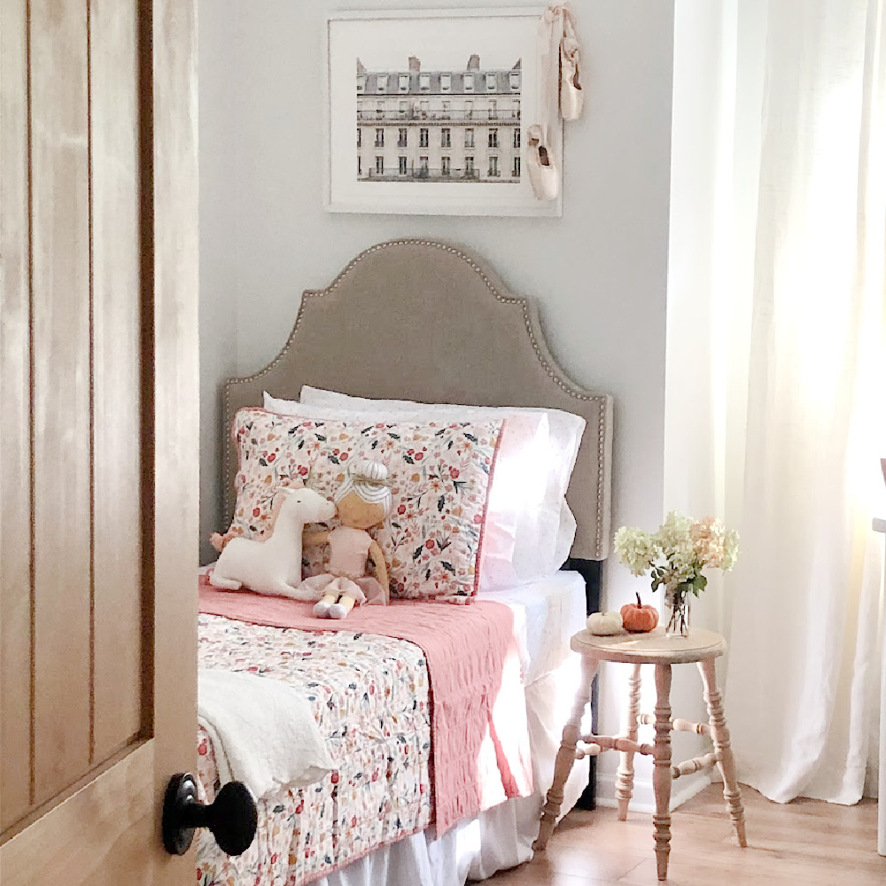 Girls bedroom with garden floral (Pillowfort) quilt, upholstered headboard, Paris framed print, and sweet ballerina and unicorn pillows - Hello Lovely Studio. #girlsroom