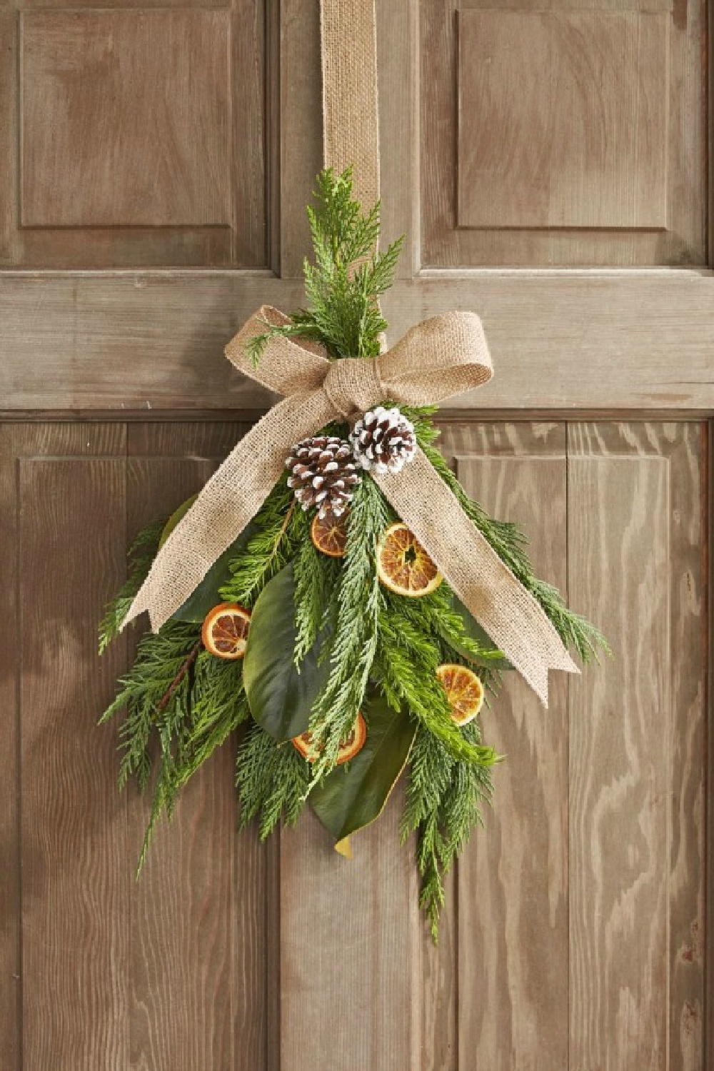 Dried oranges in a Christmas swag on door with greenery and pinecones - Country Living. #christmasdecor #handmadedecor #greenery #driedoranges