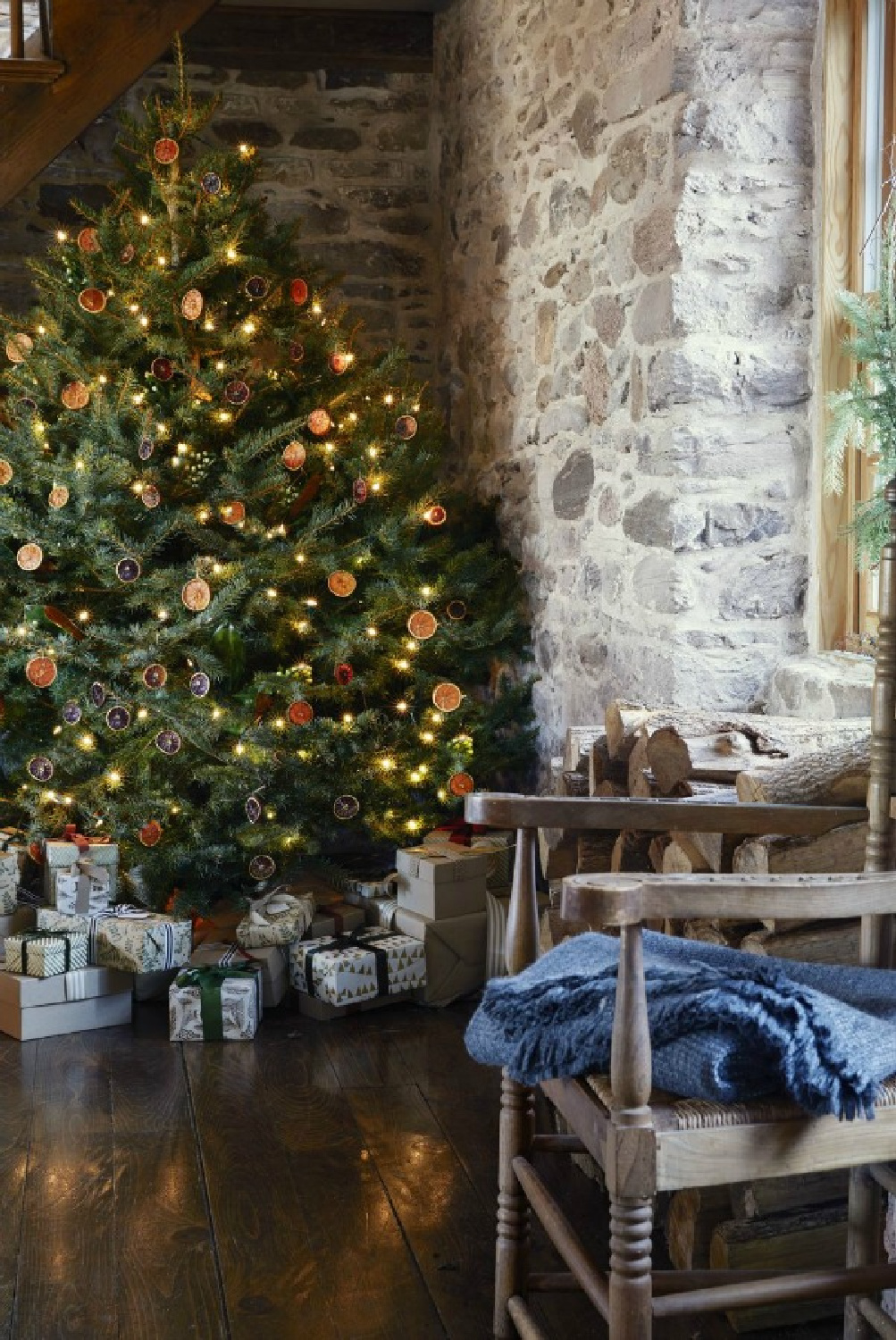 Dried oranges on a Christmas tree in a rustic stone cabin or mountain lodge - Country Living. #countrychristmas #mountainchristmas #scandichristmas #driedcitrus #garlands #countrychristmas