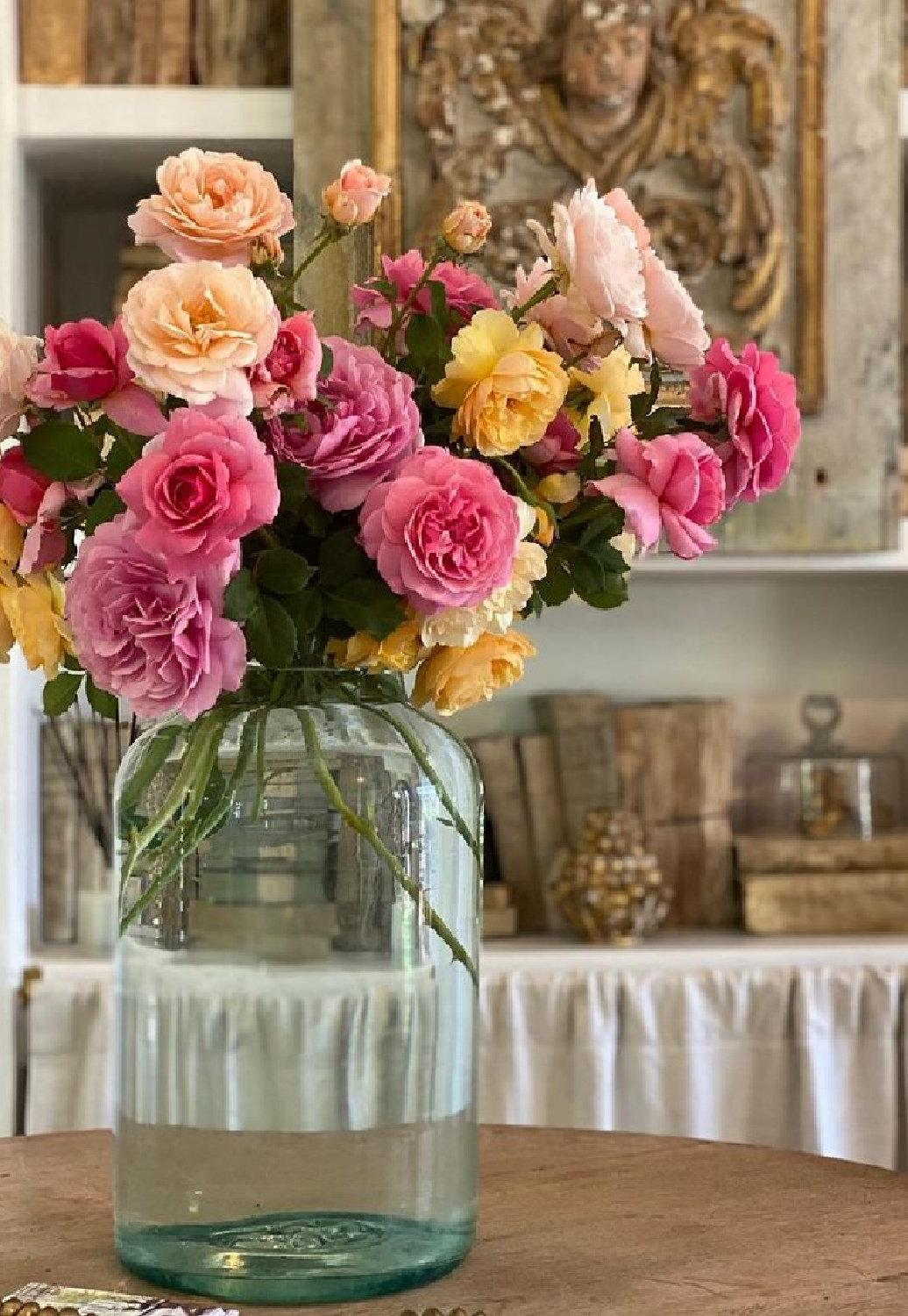 Gorgeous colorful blooming roses in a green glass jug vase in a French farmhouse inspired kitchen at Patina Farm by Brooke Giannetti. #patinafarm #frenchfarmhousekitchen #floralarrangements #frenchcountrystyle