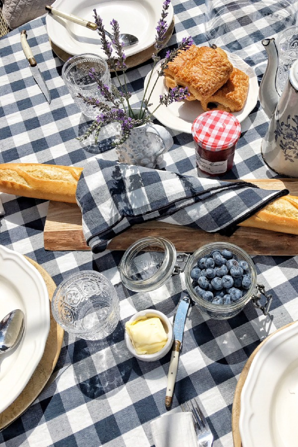 French tablescape with navy blue check linens (Maison de Vacances) from Vivi et Margot, bagutte, pastries, and berries. #vivietmargot #tablescape #check #gingham #tablecloth #baguette #dining #frenchfarmhouse