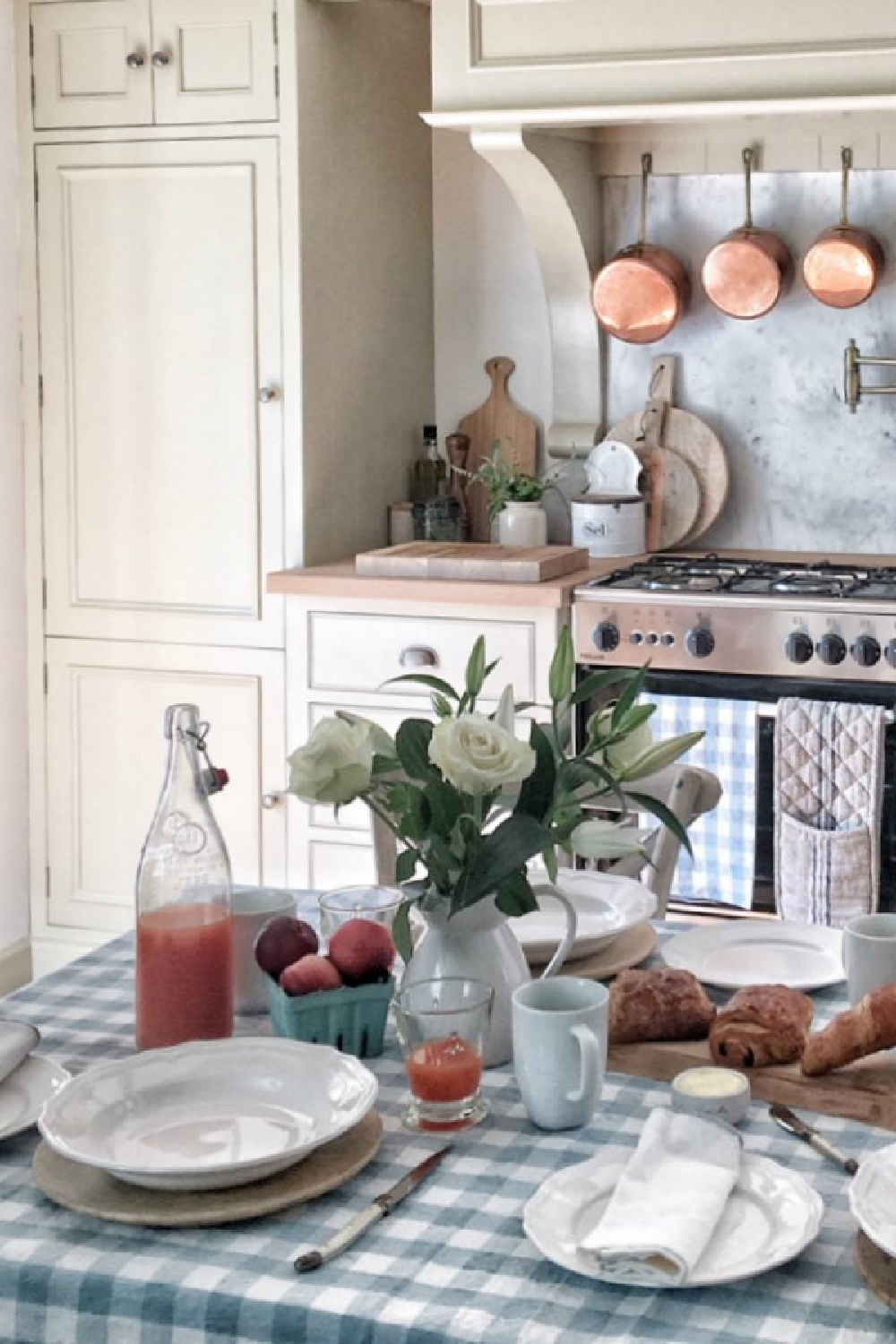French kitchen with check linens, putty cabinets, copper pans, and rustic wares from Vivi et Margot.