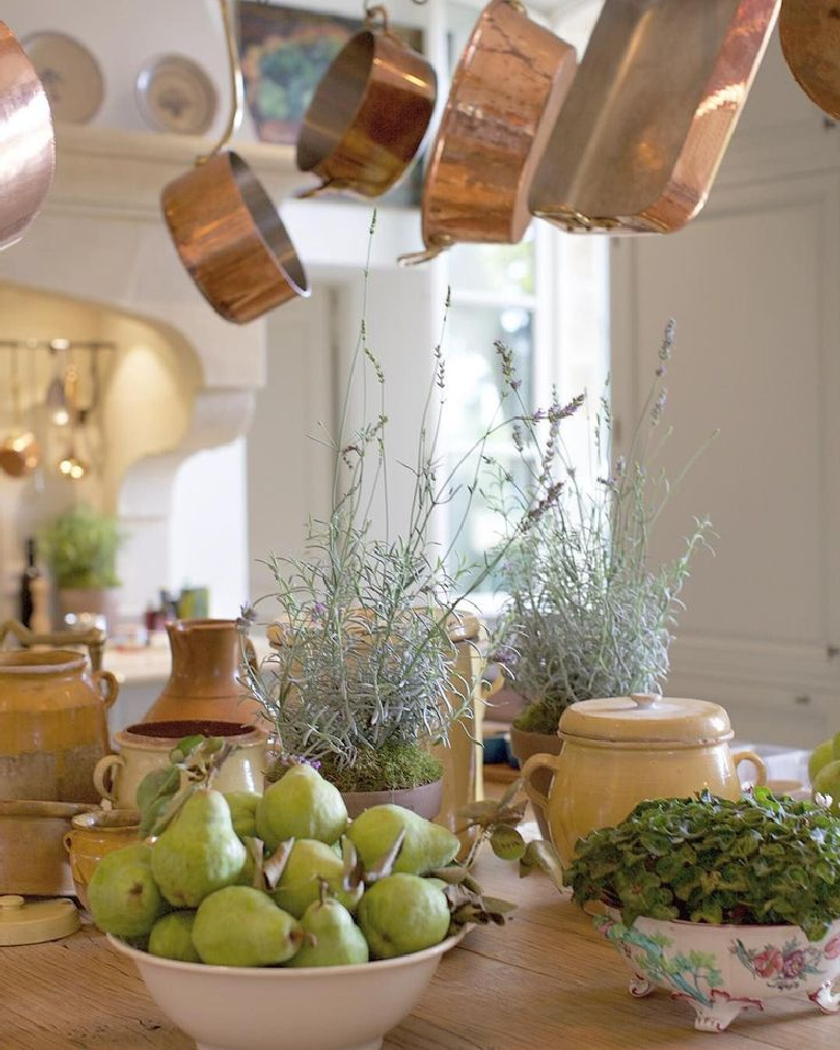 Lovely green pears and French countryside bounty on a French country kitchen island beneath copper pots from E. Dehllerin - @provencepoierers. #frenchcountry #copperpots #frenchkitchen #provencekitchen #pears #frenchpears #provencepoirers