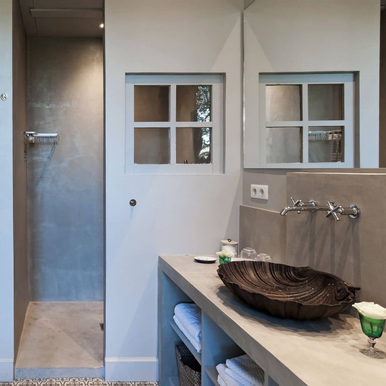 Plaster walls in modern French restored bathroom with open shelves and shell vessel sink in Avignon Hôtel Particulier, a beautifully restored 19th century mansion in the heart of Avignon’s historic center - Haven In. #modernfrench #bathroomdesign #frenchchateau #provence #frenchcountry #restoredchateau #southoffrance #aivgnonhotel